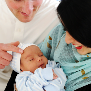 Connection is the foundation of humanity. Mum cuddling baby as Dad looks on lovingly