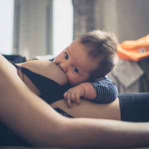 Baby breastfeeding on top of Mum who is reclined. baby looking at the camera
