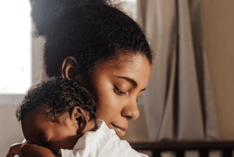 Mum cuddling baby over her shoulder