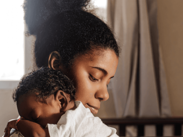 Mum cuddling baby over her shoulder