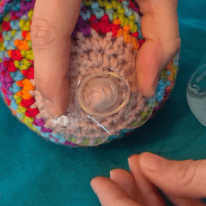 Applying the dimpled nipple shield over the nipple and holding down the edges with the fingers of one hand