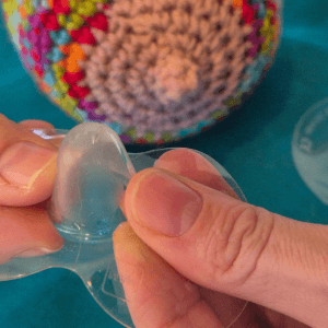 Demonstrating where to place fingers on a nipple shield to get ready for applying. Knitted breast in the background