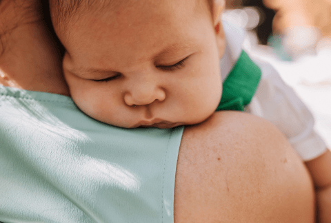 Baby sleeping over Mum's shoulder