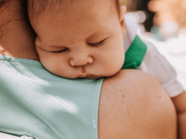 Baby sleeping over Mum's shoulder