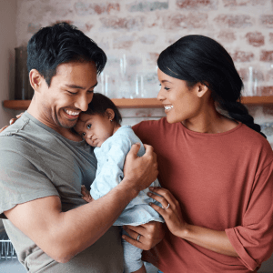parents smiling and holding baby who is becoming sleepy